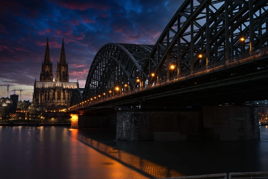 Ein Langzeitbelichtung des Kölner Doms, entlang der Hohenzollernbrücke über den Rhein bei Nacht.